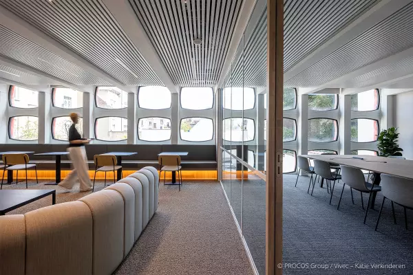 Modern kantoorinterieur met een open ruimte en een vergaderzaal, gescheiden door een glazen wand.